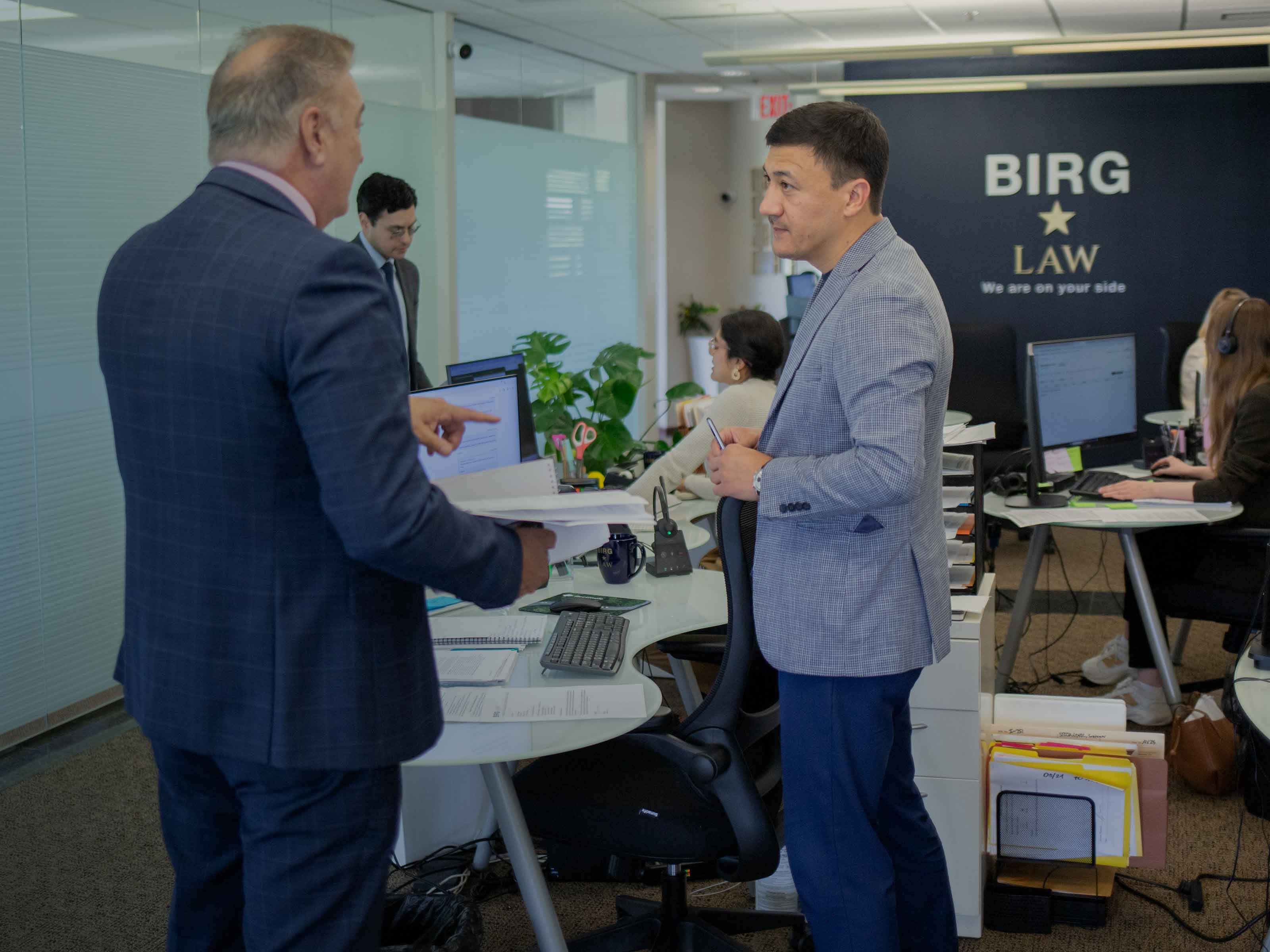 Two BIRG Law colleagues discussing a case file in the open-plan office