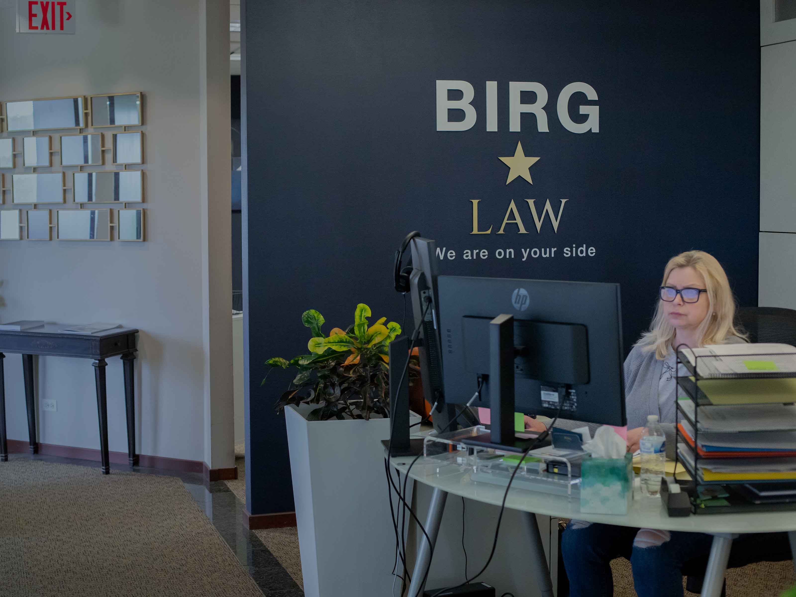 The BIRG Law reception area, with a team member working at a desk beside the branded wall