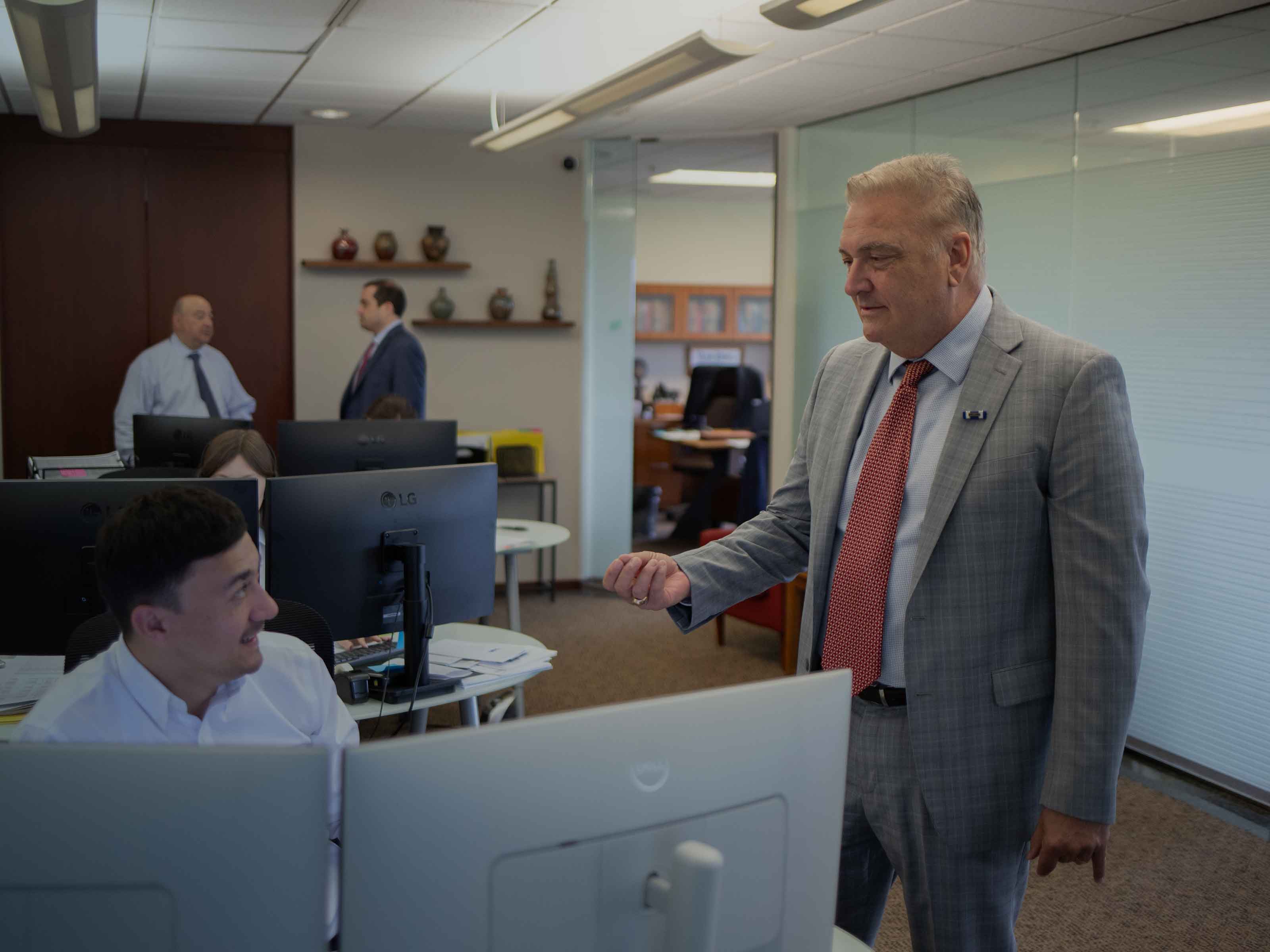 A senior BIRG Law attorney checking in with a team member at his workstation