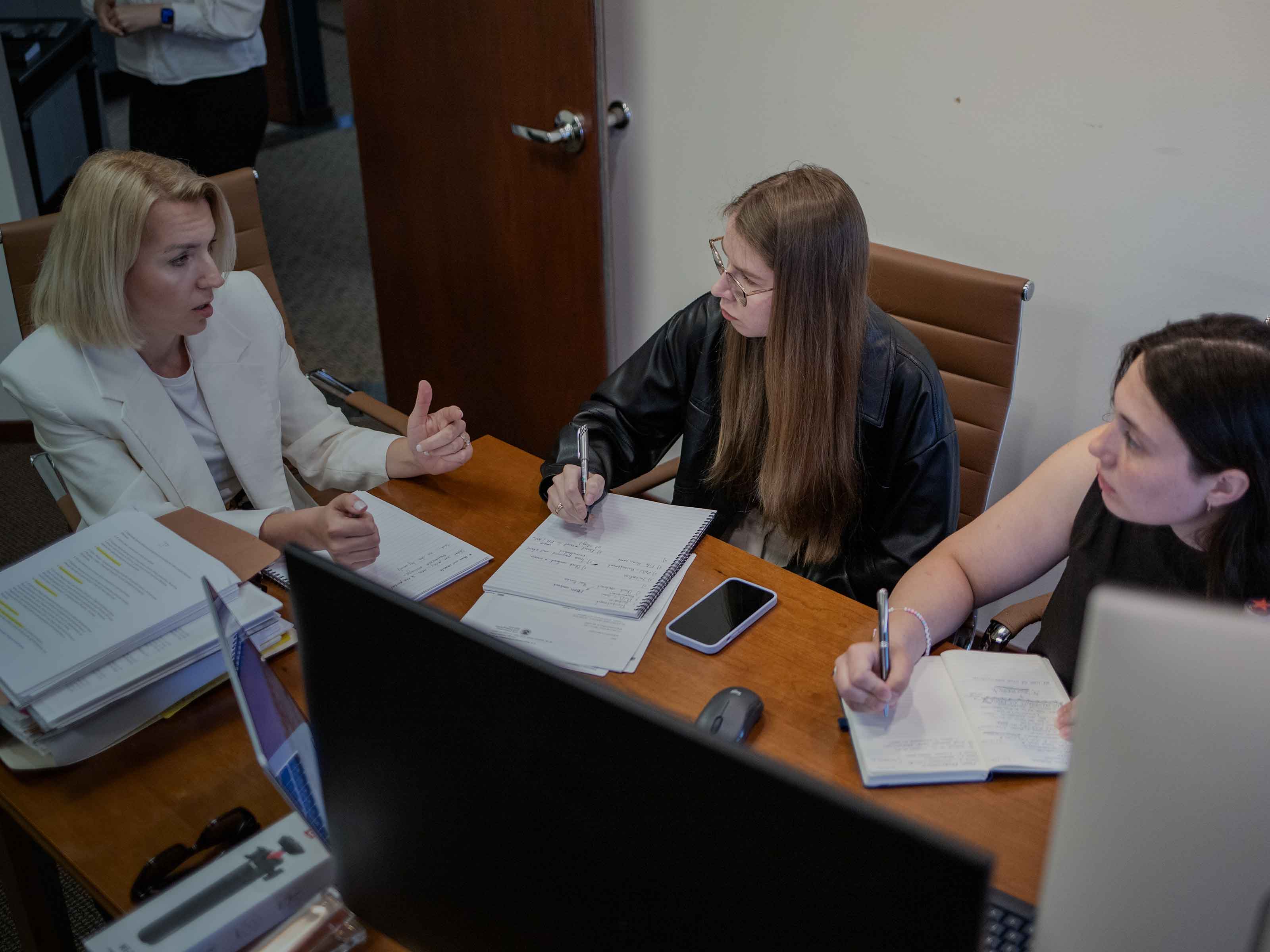 Three BIRG Law team members taking notes during a case discussion at the office