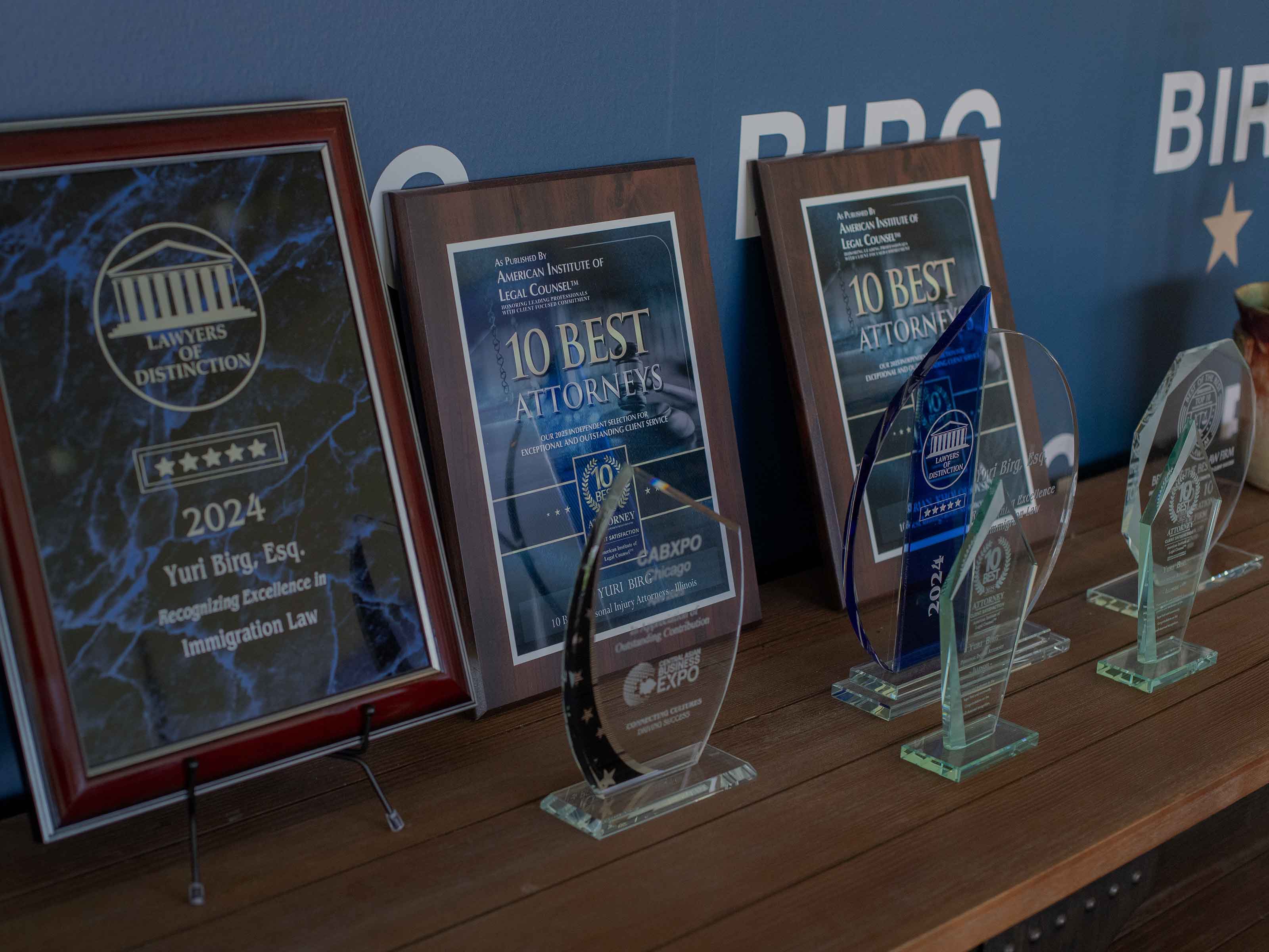 Shelf of BIRG Law awards, including a 2024 Lawyers of Distinction plaque and 10 Best Attorneys awards for Yuri Birg
