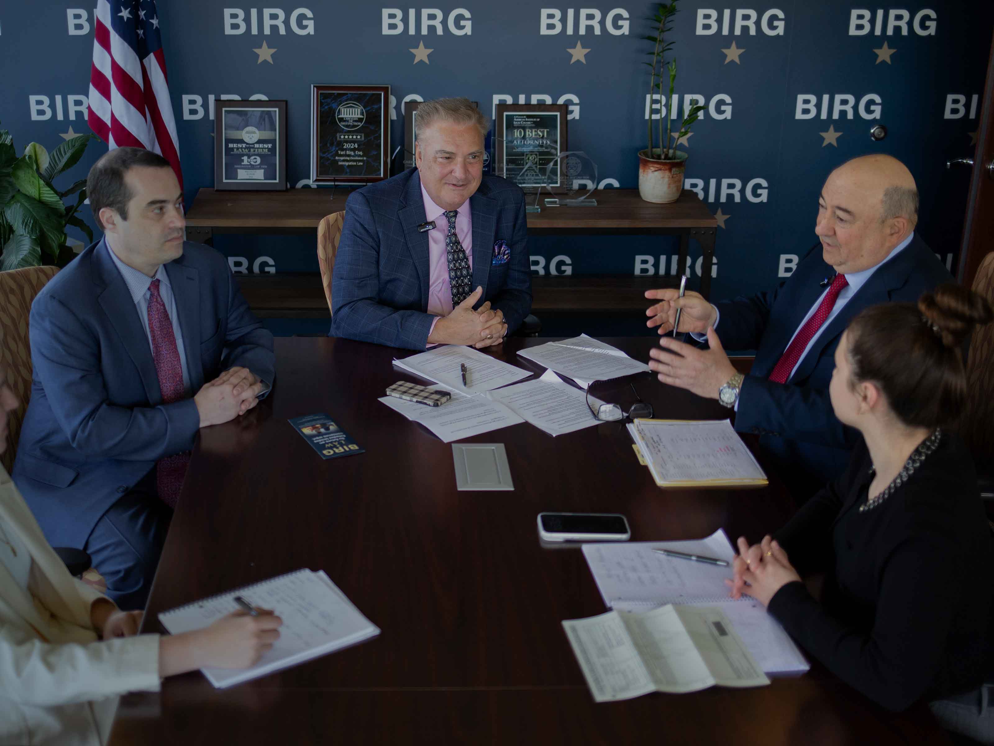 BIRG Law attorneys reviewing case documents at a conference table in front of the branded BIRG wall