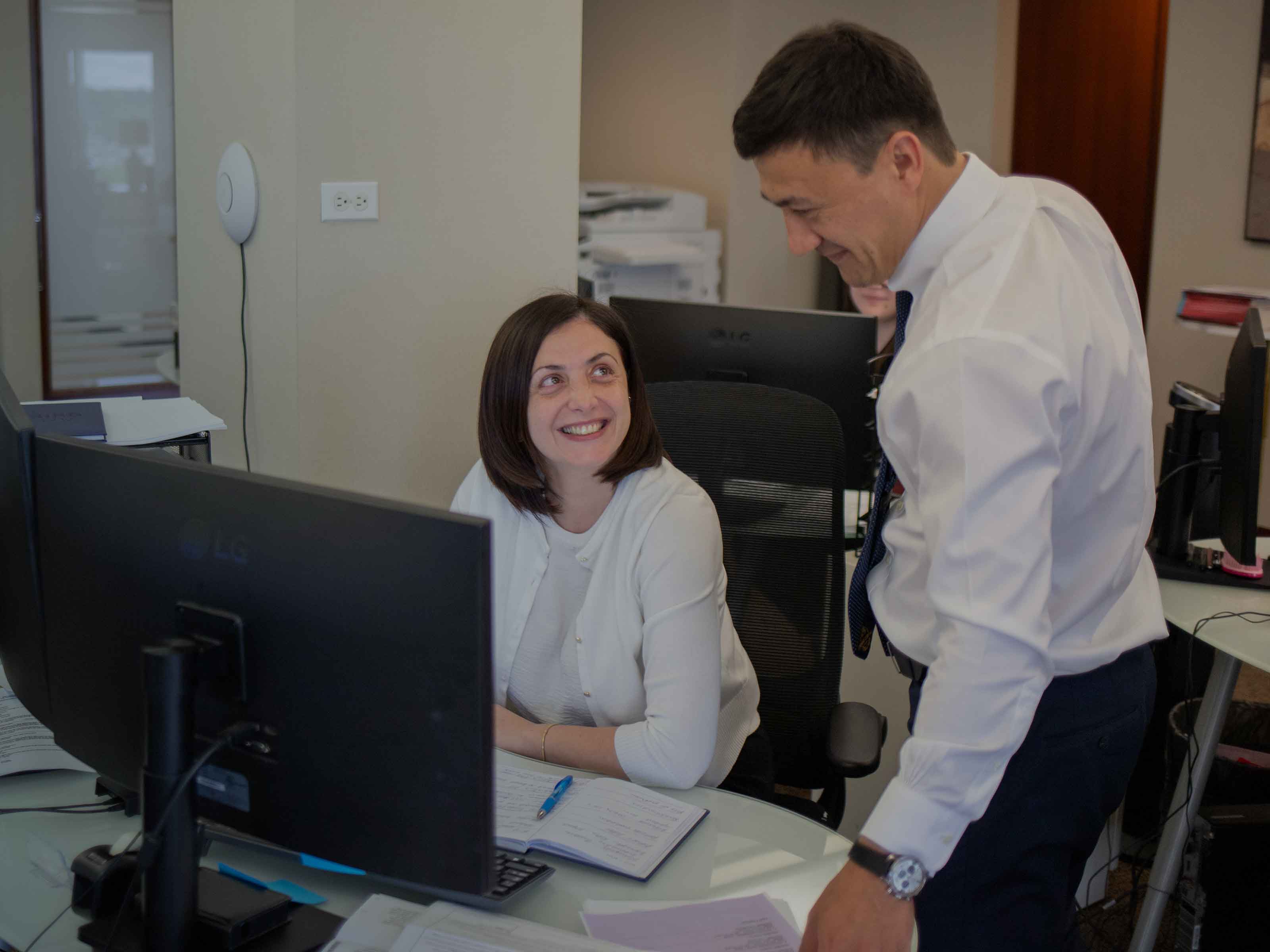 A BIRG Law paralegal and an attorney talking at a workstation in the open-plan office