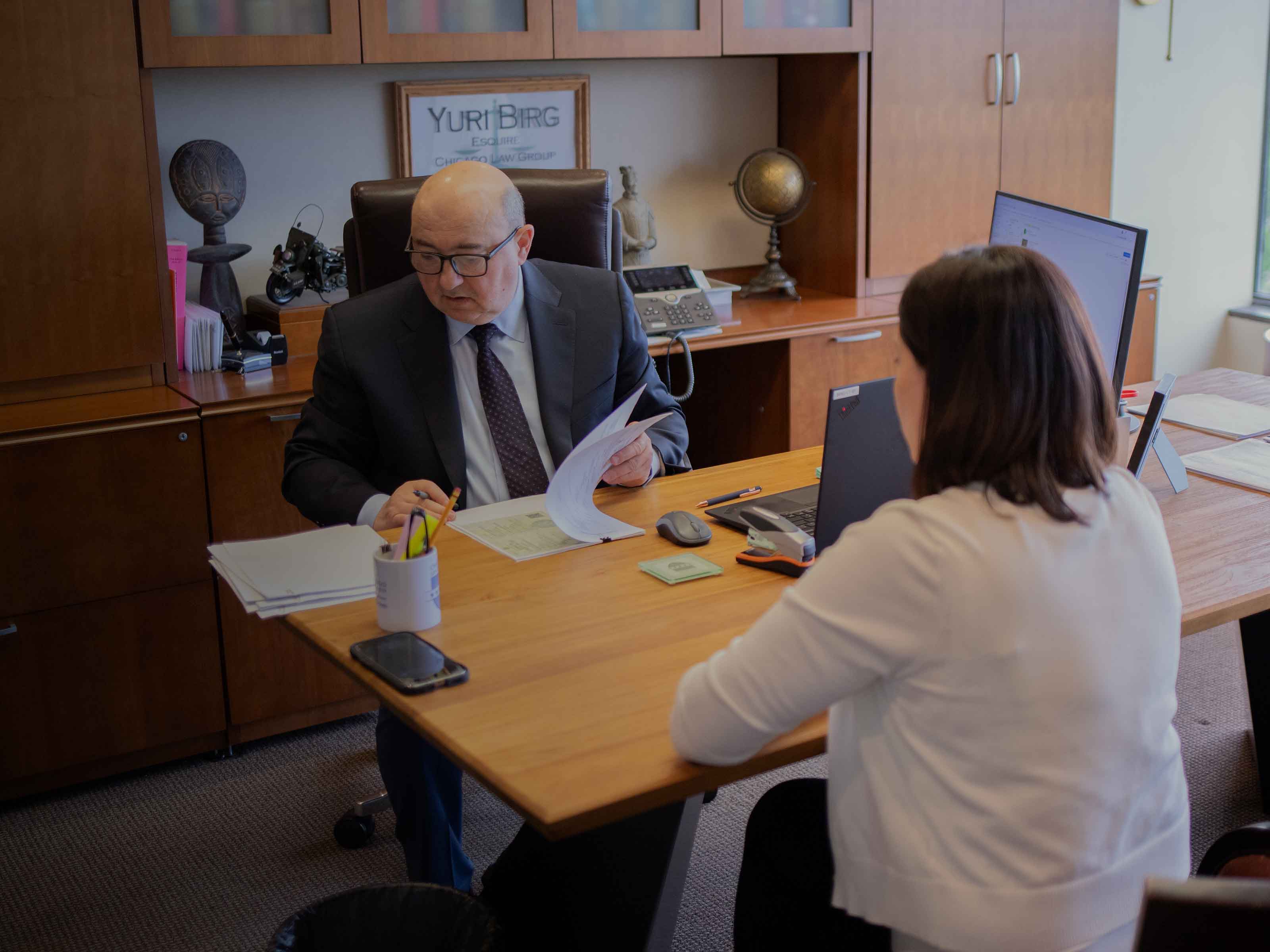 A BIRG Law attorney reviewing paperwork with a client across the desk in his office